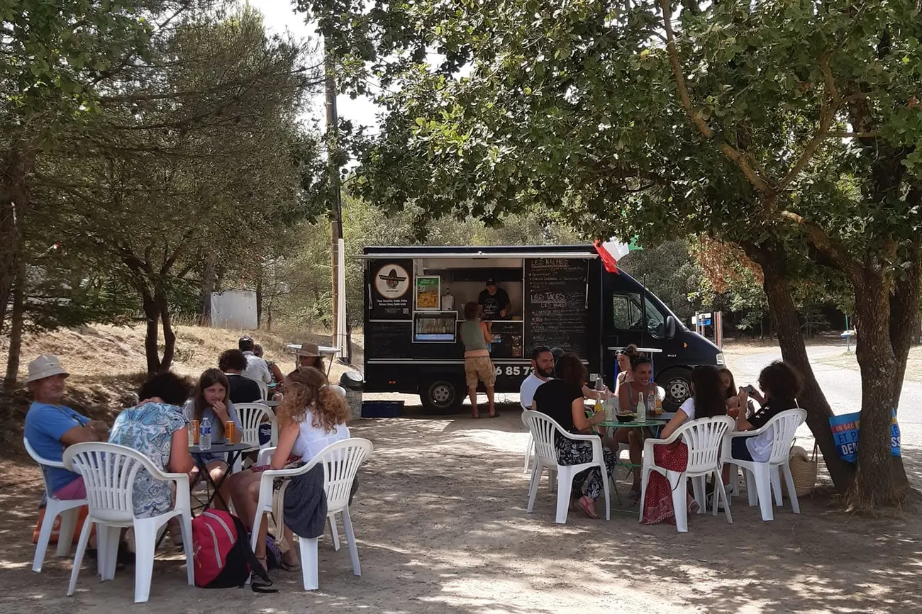 Le food truck Hot or Not installé sous les arbres, avec des tables et des clients